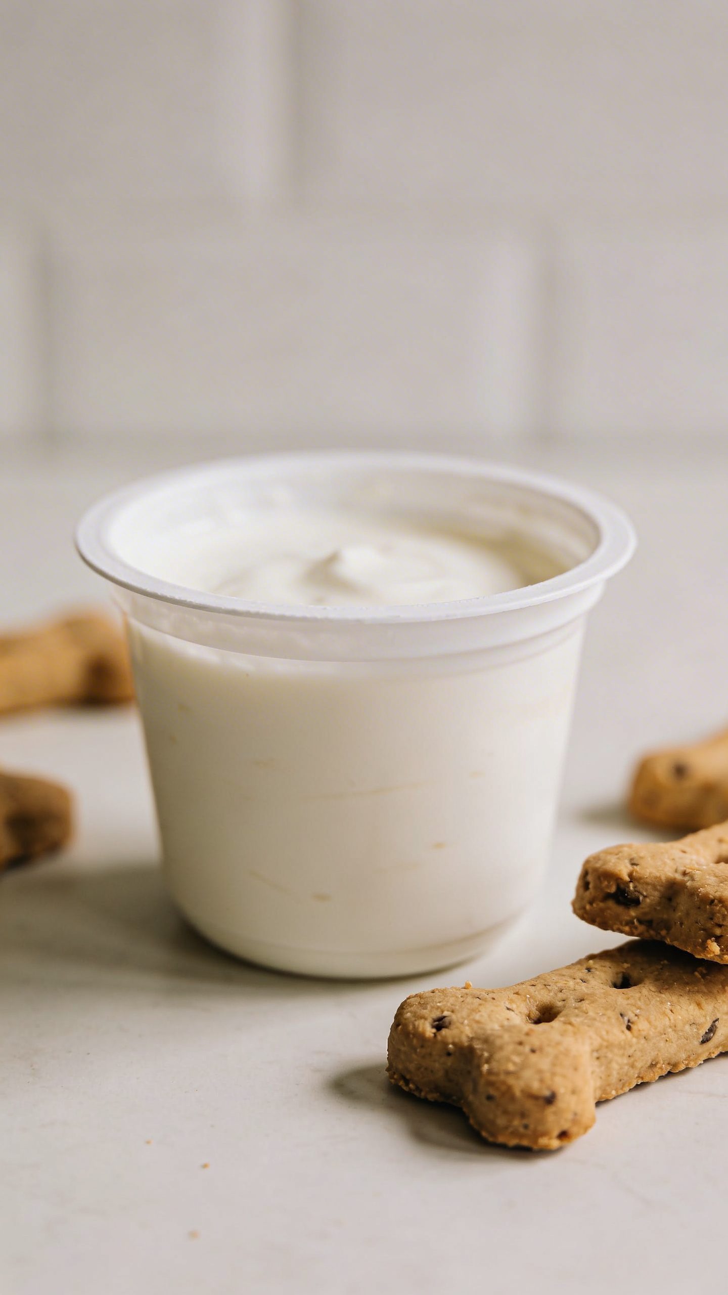 Plain Greek yogurt container beside homemade dog biscuits